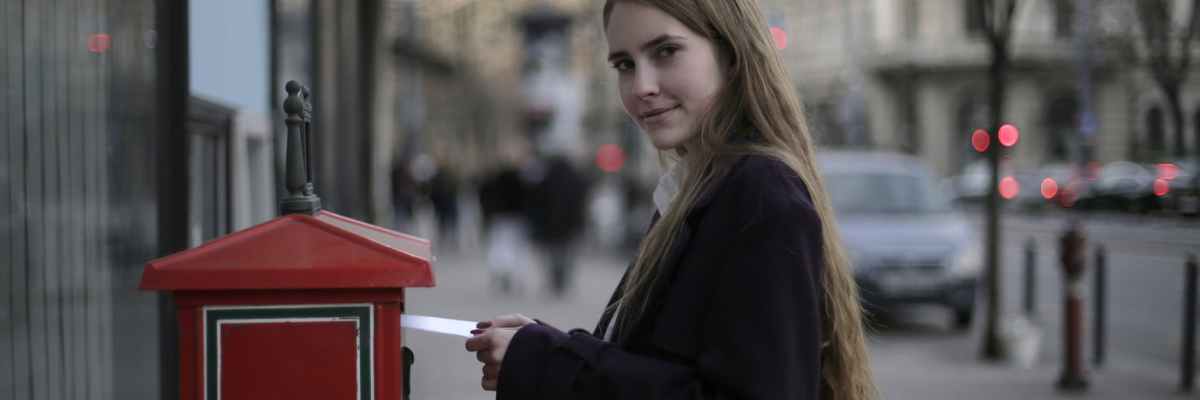 woman wearing violet coat while standing near mailbox