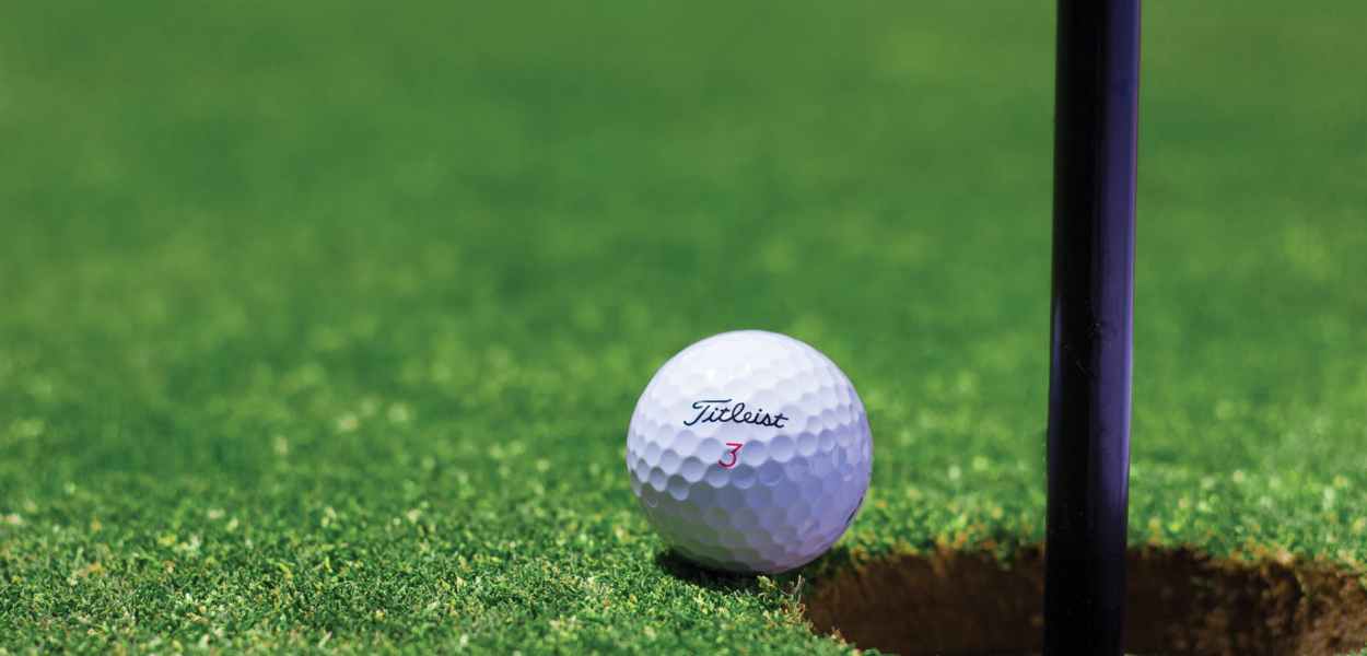 titrist golf ball near golf hole